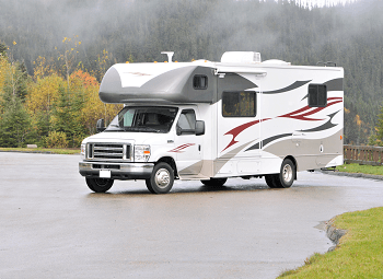 RV parked in a lot surrounded by some trees