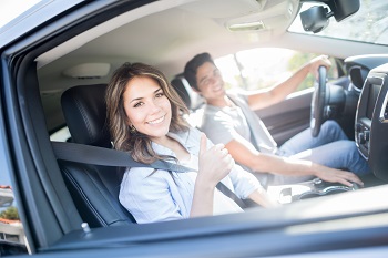 man and woman sitting in front seat of car smiling at camera